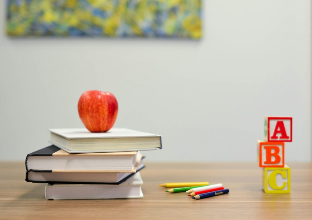 apple, books, building blocks, and colors sitting on a table